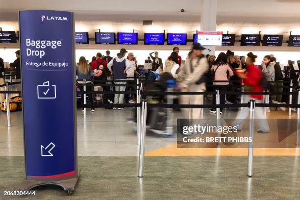Passengers stand in a line at the LATAM Airlines check-in counters at Auckland International Airport in Auckland on March 12 a day after a...