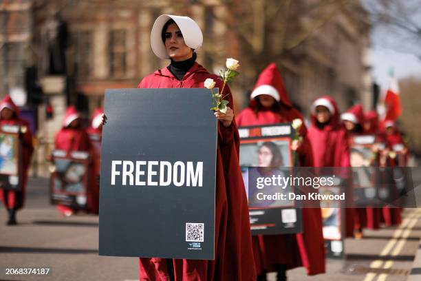 Protesters dressed as handmaids from The Handmaid's Tale march from Parliament Square to Iran's embassy to highlight repression of women in that...