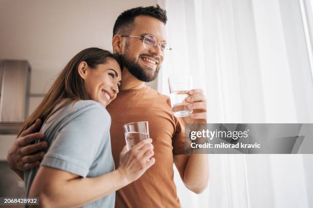 adult couple enjoying by the window. - drinkwater stockfoto's en -beelden