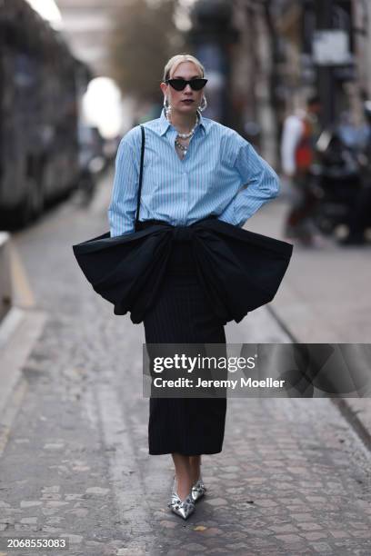 Alex Kaiser seen wearing a babyblue stripped blouse, a big black bow, black stripped long skirt and silver heels, silver necklace chains and black...