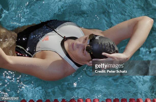 German swimmer Sandra Volker, wearing a swimsuit and swimming cap, her right hand on her head, in the water at the German Swimming Championships in...