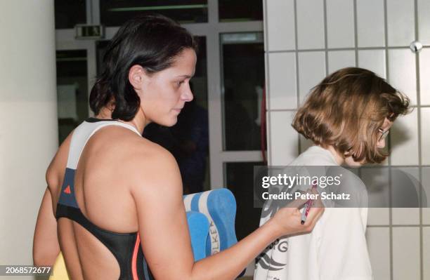 German swimmer Sandra Volker signs the back of a fan's shirt at the German Swimming Championships in Regensburg, Bavaria, Germany, November 1997. The...