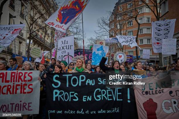 Protesters hold a banner which reads "Stop Sexism! Teachers on Strike" as thousands march through the streets of Paris to mark International Women’s...