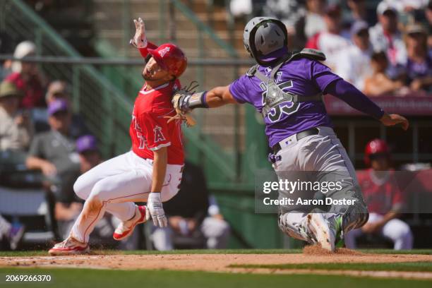 Livan Soto of the Los Angeles Angels is tagged out at home plate by Elias Dia of the Colorado Rockies in the third inning during a spring training...