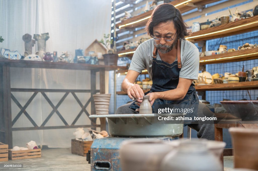 The potter working on wheel at studio.