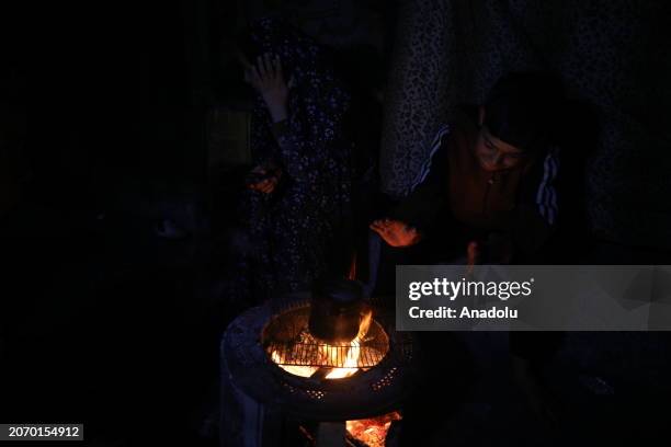 Palestinian family, who left their homes due to the Israeli attacks on the Gaza Strip, has sahur meal with za'atar, pepper sauce, a few pieces of...