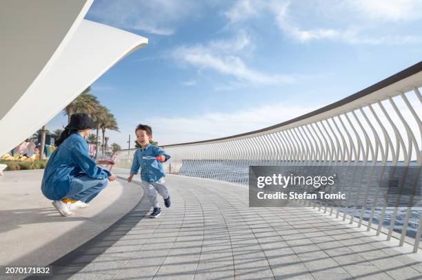 mother and toddler enjoying soap bubble wand fun by the seaside promenade - crazy baby stock pictures, royalty-free photos & images