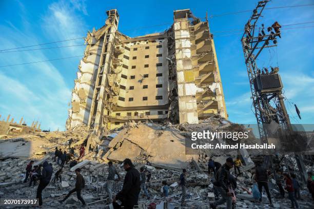 People inspect the damage and extract items from their homes after the Al-Masry Tower was targeted by Israeli air strikes on March 9, 2024 in Rafah,...