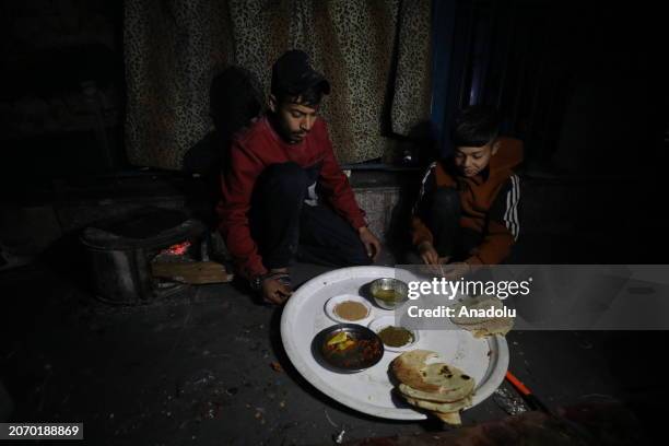 Palestinian family, who left their homes due to the Israeli attacks on the Gaza Strip, has sahur meal with za'atar, pepper sauce, a few pieces of...