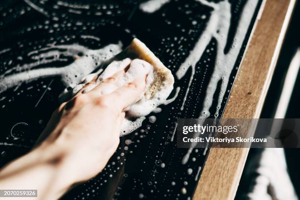 female hand cleaning induction stove with blue rag - spray bottle stock-fotos und bilder