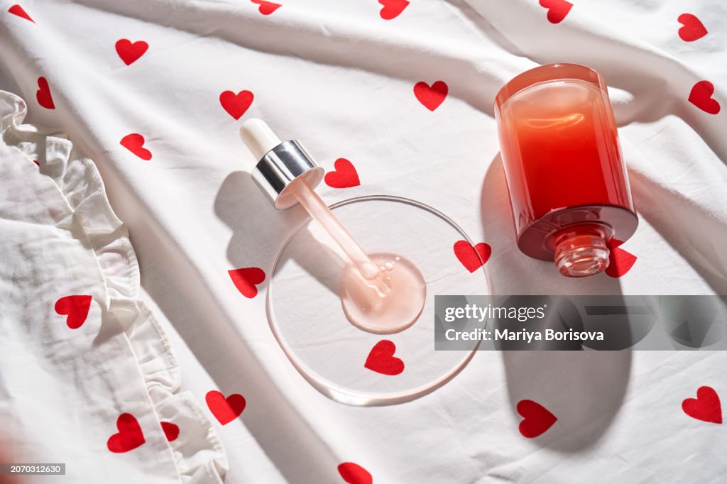 Pipette with pink serum on fabric with hearts.