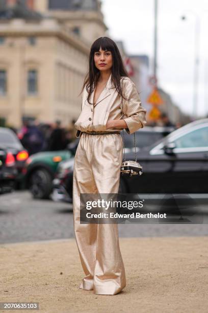 Fer Millan wears a golden shiny full look, a jacket with gathered sleeves, flared pants , a belt, a Chanel bag, outside Chanel, during the Womenswear...