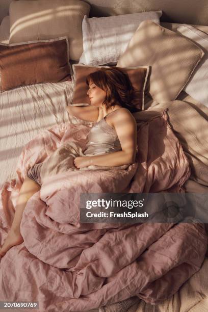 friedliche frau schläft in gemütlichem bett mit morgenlicht - frau bett stock-fotos und bilder