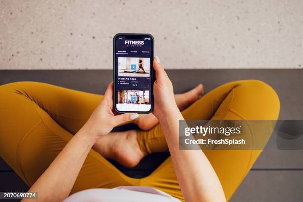 young woman using fitness app for morning yoga routine indoors - flexible screen stock pictures, royalty-free photos & images