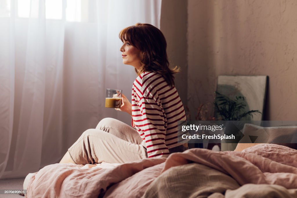 Contemplative Woman Enjoying Morning Coffee in Sunlit Bedroom