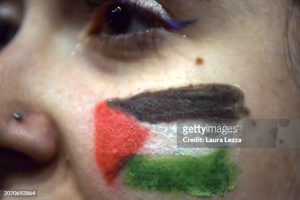 Woman takes part in a protest with a body-painted tattoo of the Palestinian flag during the International Women's Day March organised by the Italian...