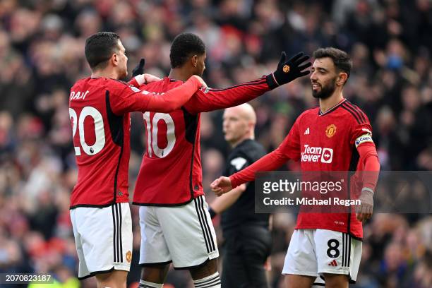 Marcus Rashford of Manchester United celebrates scoring his team's second goal from the penalty spot with teammates Diogo Dalot and Bruno Fernandes...