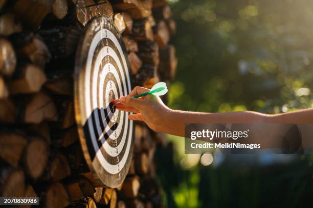 human hand pointing with dart on a dartboard in the yard - dart stock pictures, royalty-free photos & images