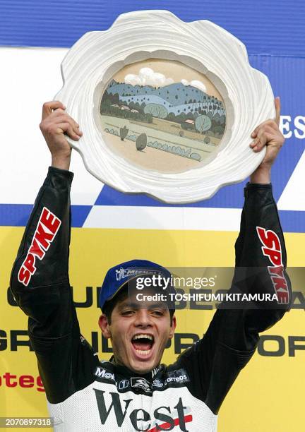 Brazilian Grand Prix rider Alex Barros raises his winning plate on a podium of the MotoGP class of the Pacific Grand Prix in Motegi, 06 October 2002....