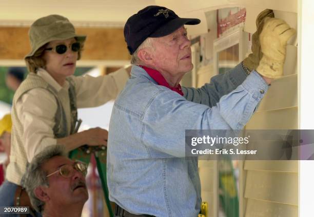 Former US President Jimmy Carter and former First Lady Rosalyn Carter attach siding to the front of a Habitat for Humanity home being built June 10,...