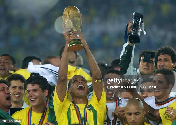 Brazil's midfielder Rivaldo hoists the World Cup trophy as the whole Brazilian team cheers after winning 2-0 against Germany in match 64 of the 2002...