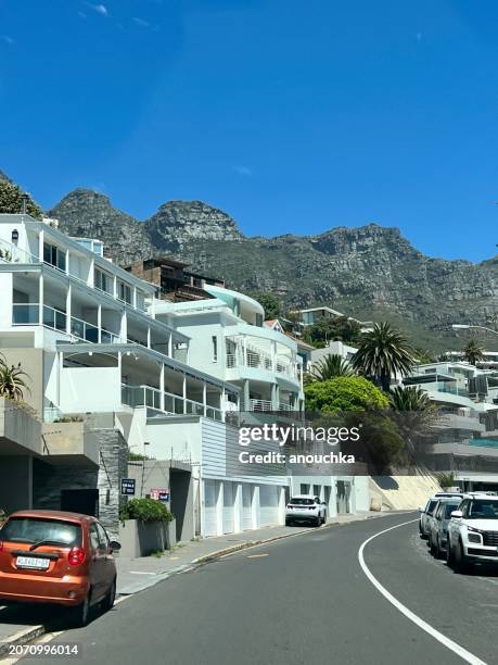 houses along the road and cars parked, cape town, south africa - camps bay stock pictures, royalty-free photos & images