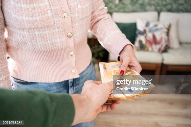 a woman is handing over a stack of bills to a man - money laundering stock pictures, royalty-free photos & images
