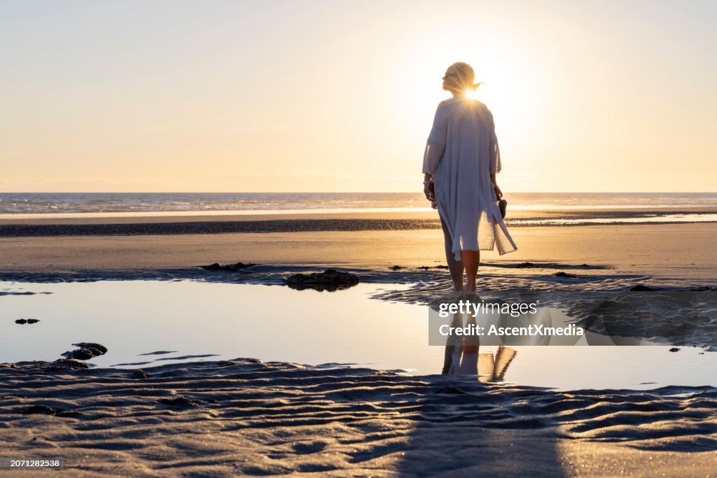Mature woman walks along empty beach