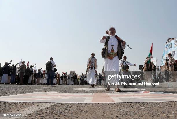 Yemen's Houthi followers from state servants carry weapons and step on a British Union Jack flag as they parade during a rally held against the...