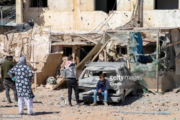Youth sits by a damaged vehicle outside a destroyed building in the aftermath of an overnight Israeli airstrike on the city of Baalbek in east...