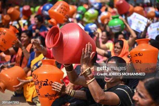 Activists and members of the Bharatiya Janata Party hold empty water pots as they shout slogans during a protest against the state government over...
