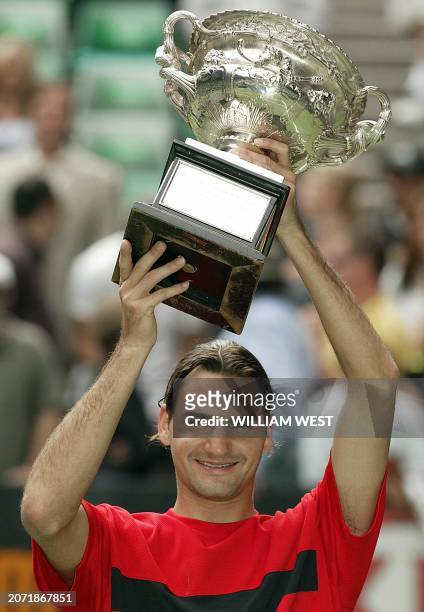 Roger Federer of Switzerland holds up the winner's trophy following his victory over Marat Safin of Russia in the men's final at the Australian Open...