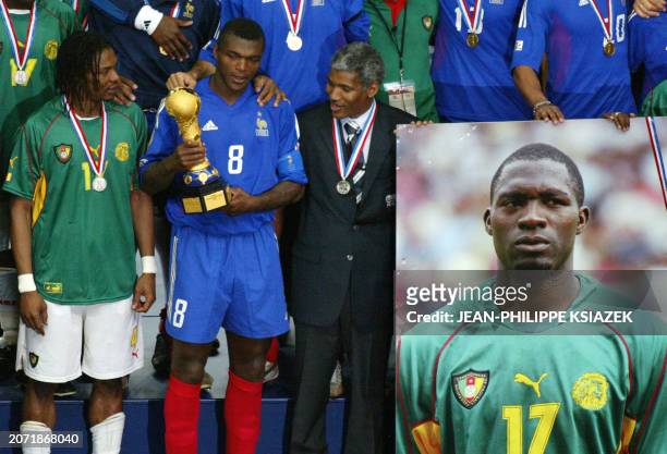 Cameroonian captain Rigobert Song and French captain Marcel Desailly hold the trophy next Cameroonian President of soccer federation and a picture of...