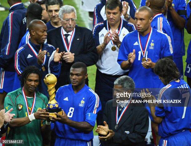French captain Marcel Desailly and Cameroonian captain Rigobert Song hold the trophy next Cameroonian President of soccer federation at the end of...