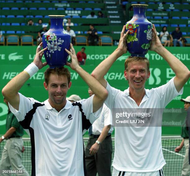 Wayne Arthurs and Paul Hanley of Australia hold championship trophies at an award ceremony after the doubles final against Zhu Benqiang and Zeng...