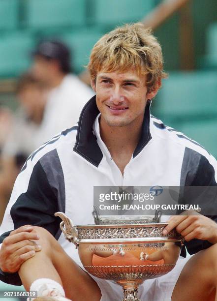 Spain's Juan Carlos Ferrero is seated with his trophy, 08 June 2003 in Paris, following his Roland Garros French Tennis Open final match against...