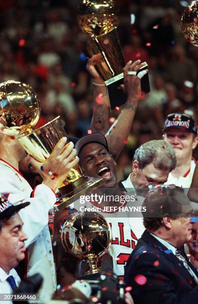 Chicago Bull player Michael Jordan is surrounded by NBA Championship trophies after his team defeated 13 June 1997 the Utah Jazz 90-86 to win the...