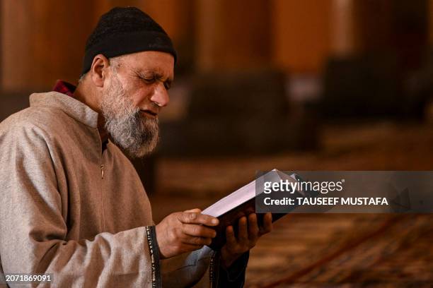 Muslim devotee reads the Koran, the holy book of Islam, on the first day of the holy fasting month of Ramadan at the Jamia Masjid in downtown...
