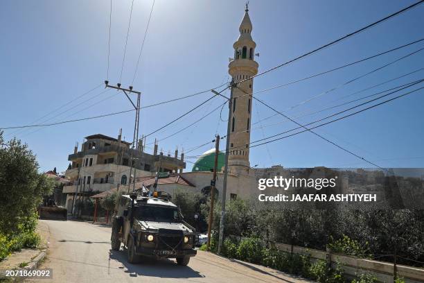 An Israeli military vehicle patrols along a street during a raid at the Jenin refugee camp area in the occupied West Bank on March 12, 2024.