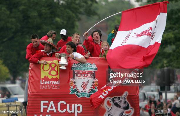 Liverpool players Jose Reina and Fernando Morientes watch as Robbie Fowler waves a giant flag with the English FA Cup as they tour the streets of...