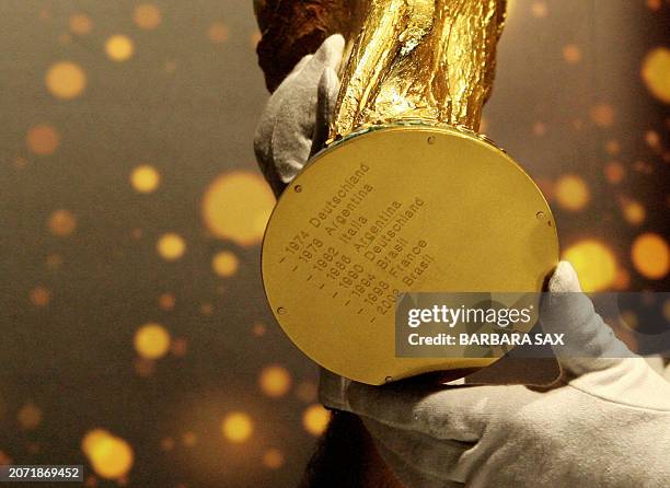Security officer holds the FIFA World Cup trophy with its last winners engraved in its bottom side as the trophy is presented to the public 12 May...