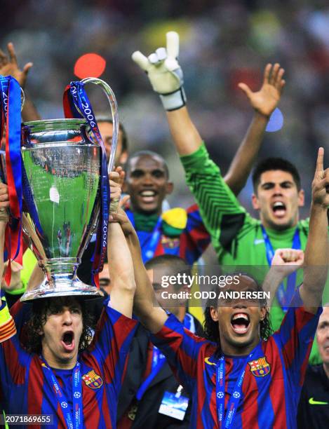 Barcelona's Spanish defender and team captain Carles Puyol and his Brazilian teammate Ronaldinho celebrate with the UEFA Champion's League trophy...