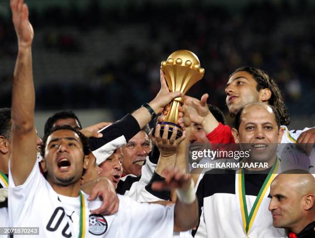 Egyptian forward Ahmed 'Mido' Hossam poses with teammates, holding the trophy, at the end of the African Nations Cup final football game at Cairo's...