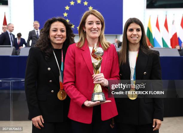 European Parliament President Roberta Metsola poses with a FIFA World Cup trophy and Spain's national women's football team players Ivana Andres and...