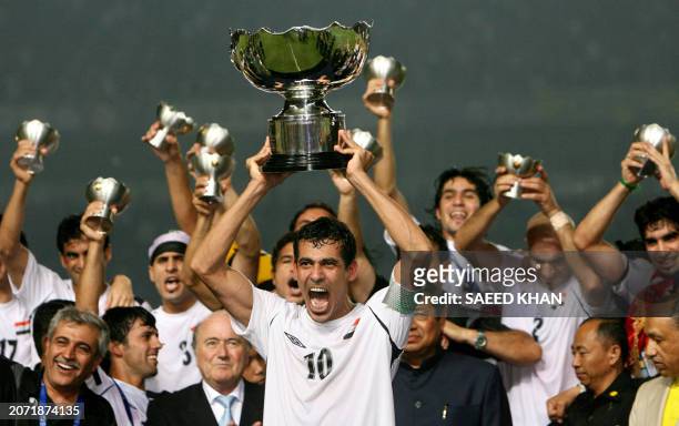 Iraq's captain Younis Mahmoud holds up the winning trophy as he along with teammates celebrate at the end of the final match of the Asian Football...