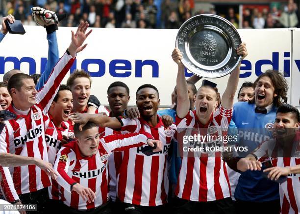 Dutch PSV Eindhoven captain hoists the trophy flanked by his teammates as they celebrate their victory 1-0 over Vitesse in Netherlands 'First League...