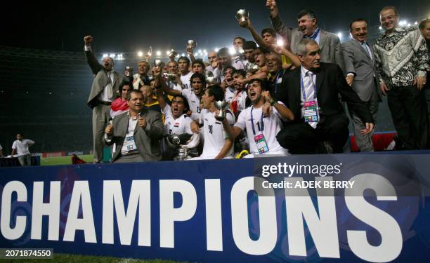 Jubilant Iraq's national football team members pose with their winning trophy during the presentation at the end of the final match of the Asian...
