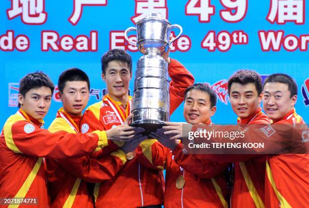 China's team members Ma Long, Chen Qi, Wang Liqin, head coach Liu Guoliang, Wang Hao and Ma Long raise the trophy on the podium of the World Team...