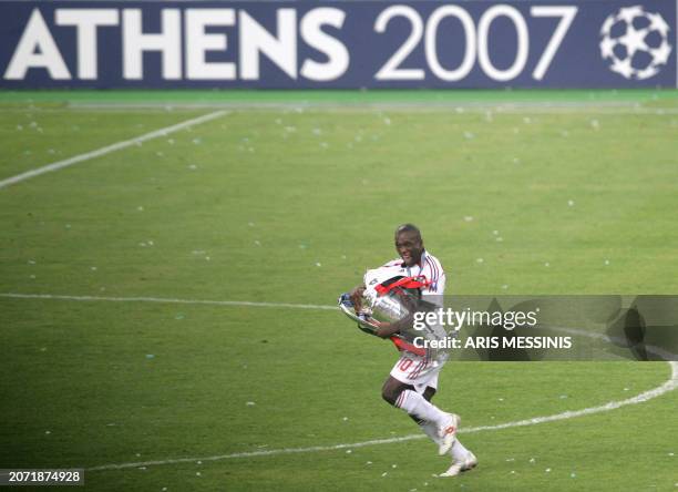 Milan's Dutch midfielder Clarence Seedorf runs with the trophy after winning the Champions League final football match, at the Olympic Stadium, in...