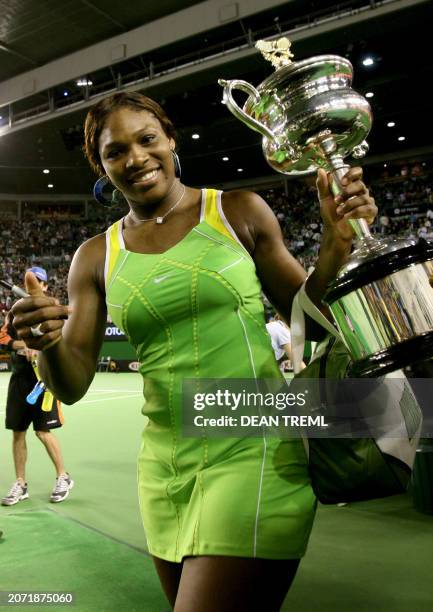 Serena Williams of the US gestures as carries the winner's trophy off the court while celebrating victory in her women's singles final match against...